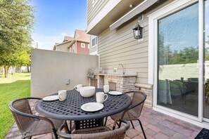 Eine Terrasses mit rundem Tisch, Stühlen und Grill.