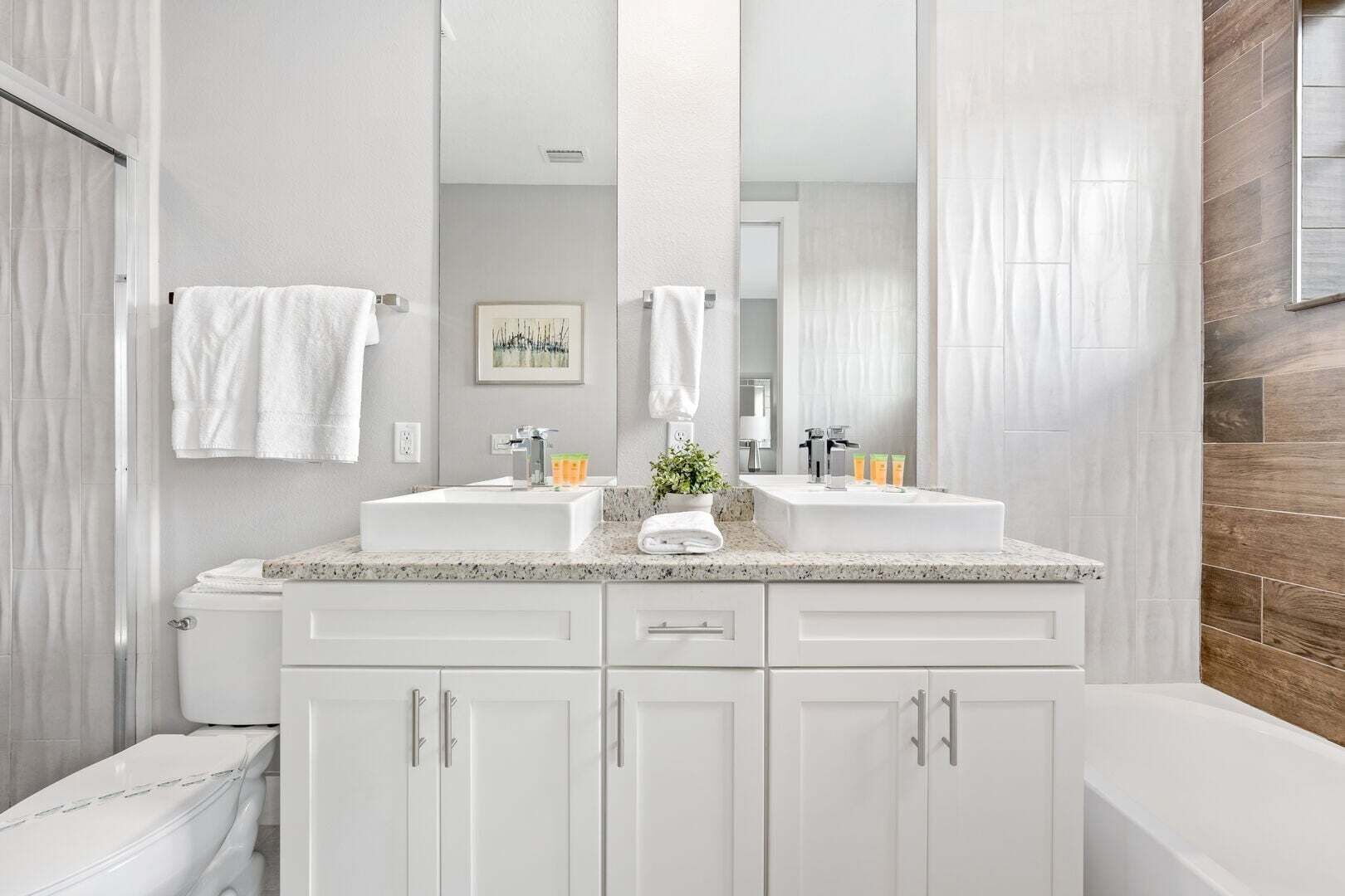 Une salle de bain moderne avec deux lavabos, un grand miroir et des meubles blancs.