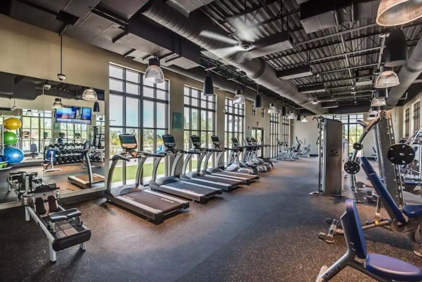Gimnasio con cintas de correr, máquinas de pesas y pelotas de ejercicio.