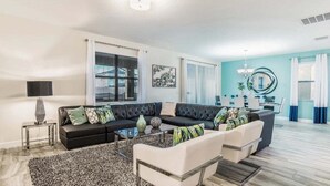 Uma sala de estar moderna com um sofá seccional, uma mesa de centro e um espaço de jantar com uma mesa redonda e cadeiras.