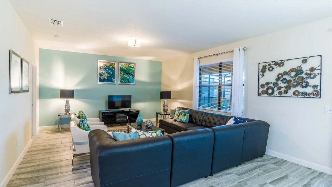 A living room with a sectional sofa, a flat-screen TV, and artwork on the walls.