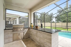Eine Küche mit Grill, Fenster und Pool.