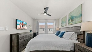 Quarto com cama, ventoinha no teto, televisão, obras de arte e janela com persianas.