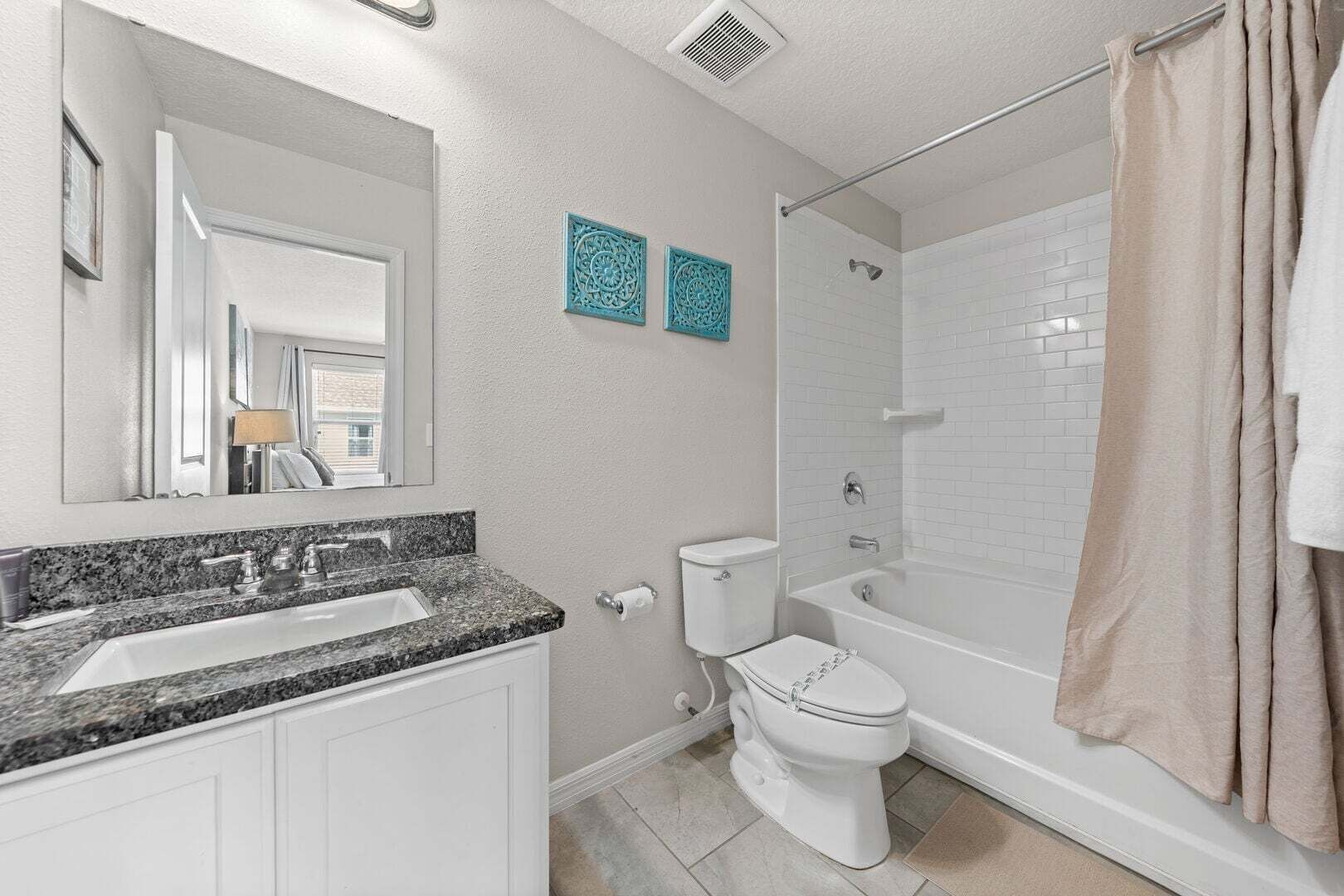 A bathroom with a granite countertop sink, a toilet, and a walk-in shower.