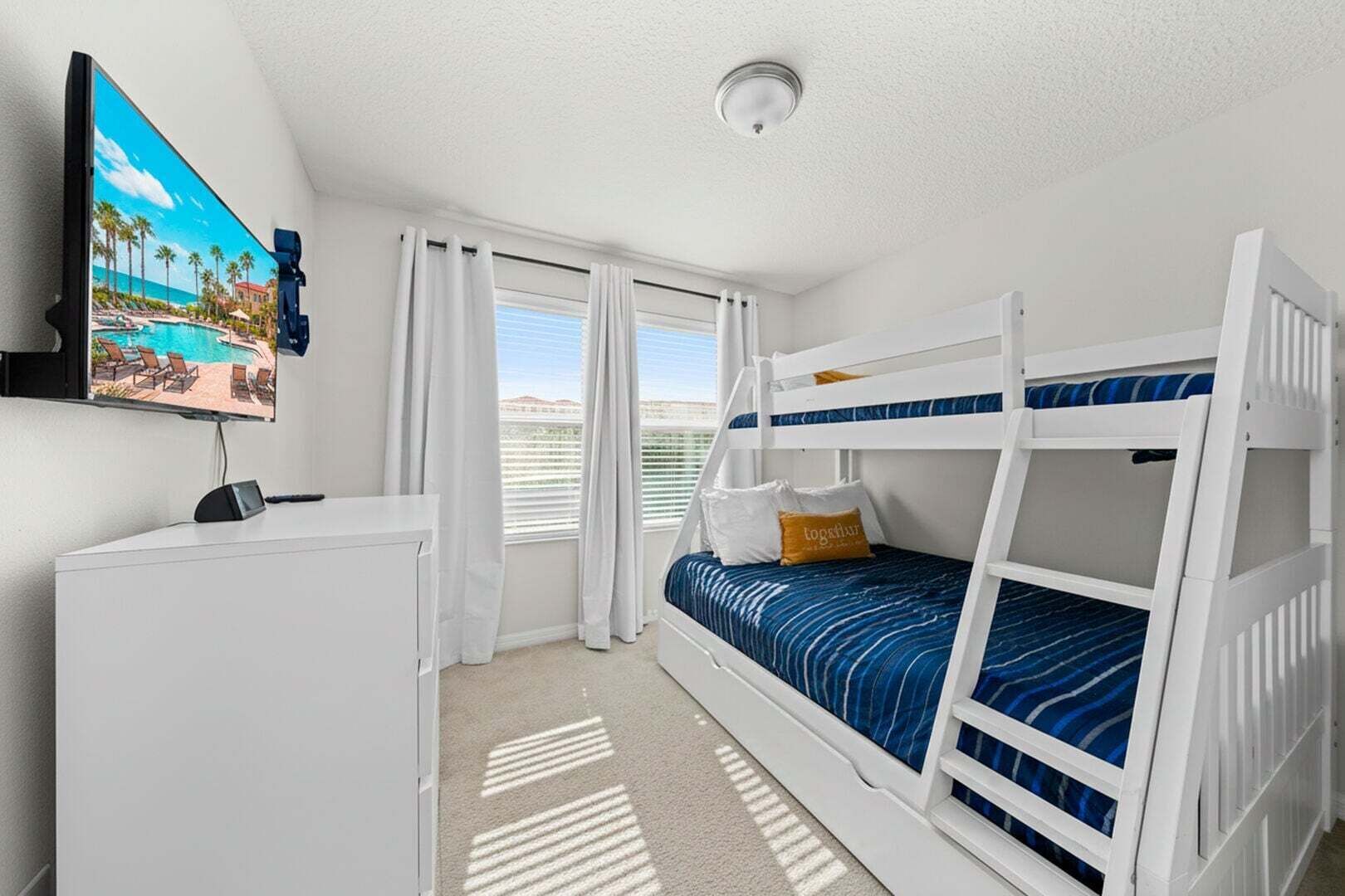 Una habitación con literas, un escritorio, un televisor y una ventana con cortinas.