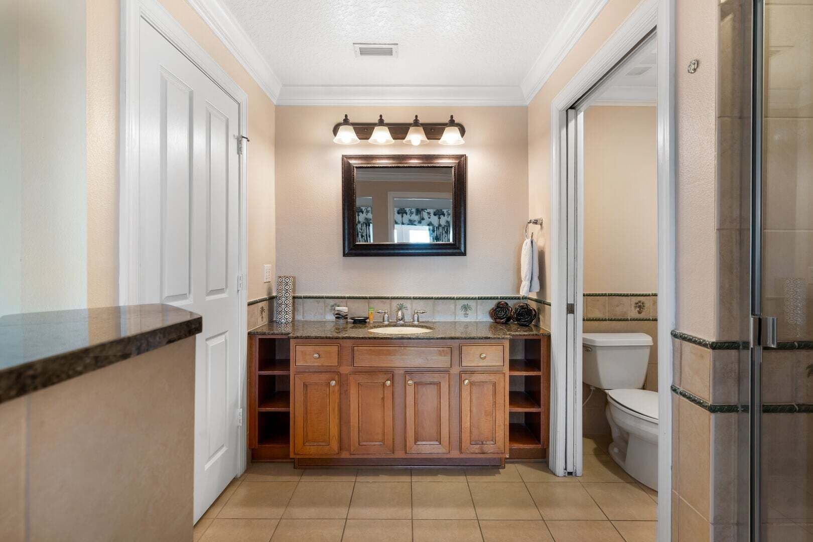 Un baño con tocador, lavamanos, espejo y ducha.