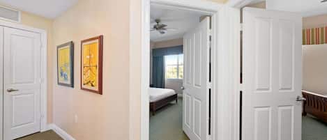 Une chambre d’hôtel avec un lit, une porte donnant sur une autre pièce et un ventilateur de plafond.