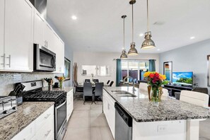A modern kitchen with granite countertops, stainless steel appliances, and pendant lighting. - Wonderful Villa 5min From Theme Park Hot Tub & BBQ 112 (Kissimmee)