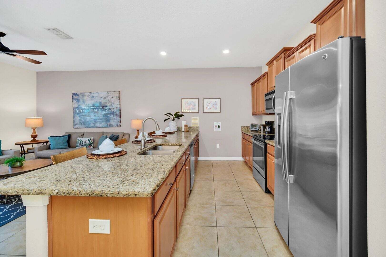 A modern kitchen with granite countertops, stainless steel appliances, wooden cabinets, and a central island.