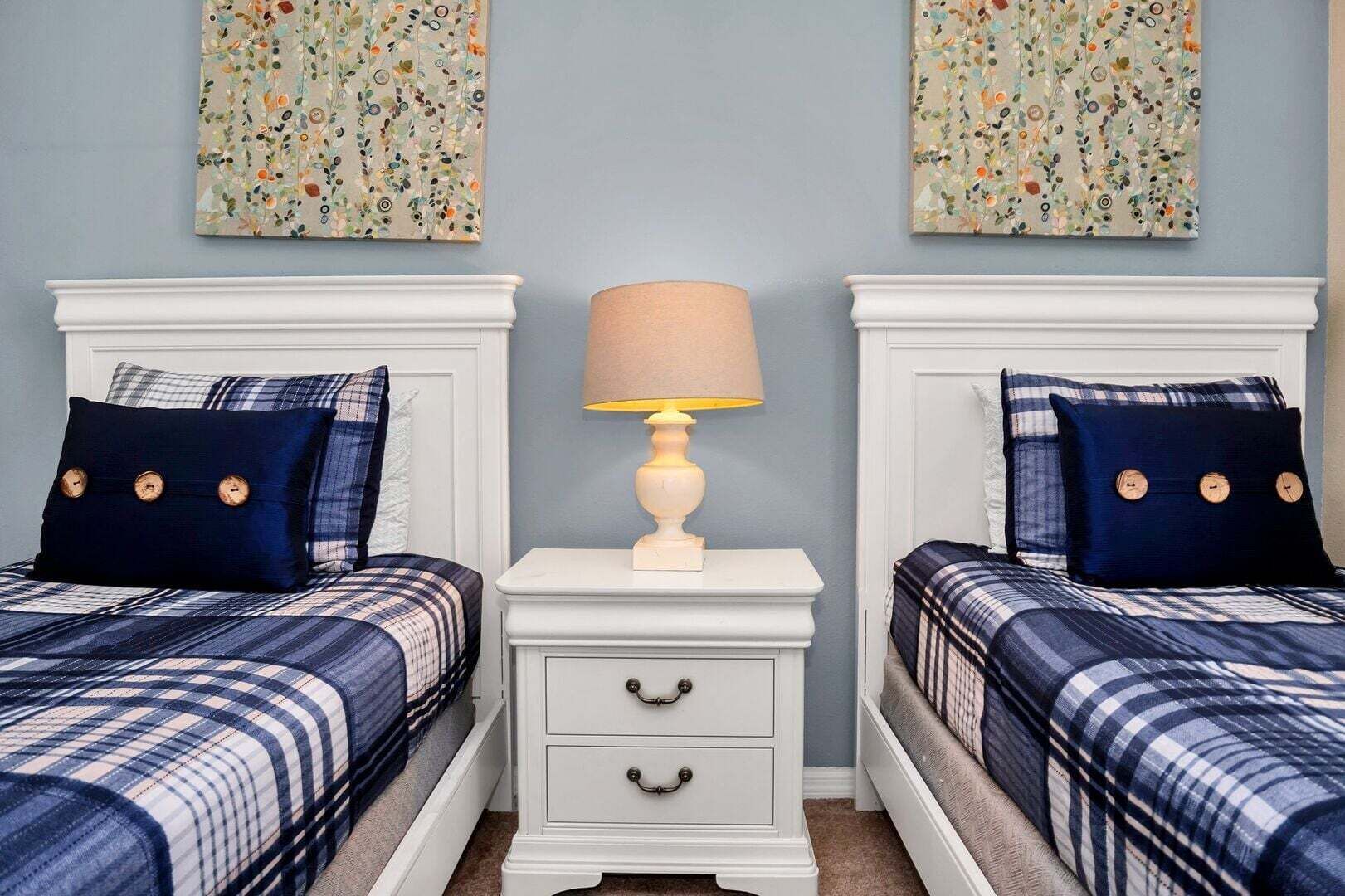 Une chambre avec deux lits, une table de chevet et une lampe.