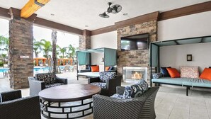 An outdoor lounge area with wicker furniture, a fire pit, and a TV mounted on the wall. - Spacious 5-bedroom Villa With Private Pool in Davenport (Davenport)