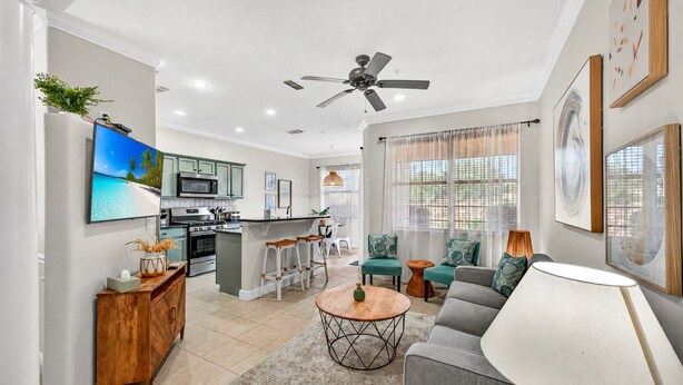 A modern kitchen with a central island, a dining area with a round table, and a living room with a sofa and a lamp. - Cozy 3BR Townhome 5 Miles From Disney (Kissimmee)