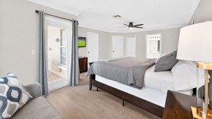 A bedroom with a bed, a ceiling fan, a TV, and a door leading to a balcony. - Cozy 3BR Townhome 5 Miles From Disney (Kissimmee)