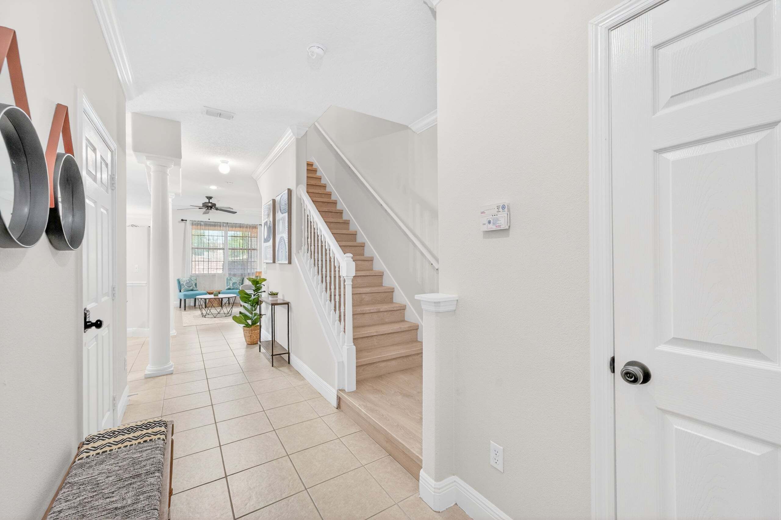 A hallway with a staircase, a door, and a bench.