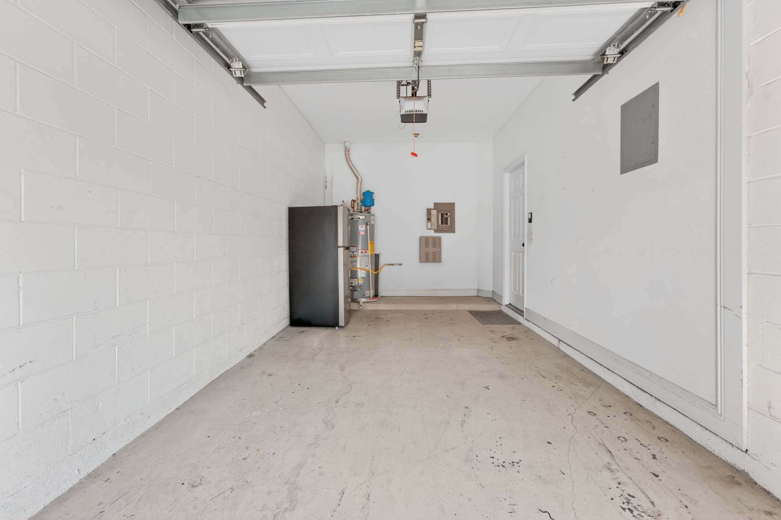 A hallway with white brick walls, a ceiling with visible ductwork, and a door at the end.