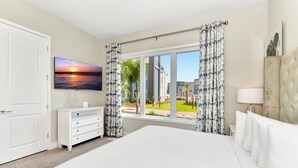 Una camera d'albergo con un letto grande, un comò, una televisione e una finestra con tende.