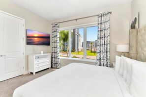 A hotel room with a large bed, a dresser, a TV, and a window with curtains. - Private Condo, Ideal for Groups - apt 138 (Kissimmee)