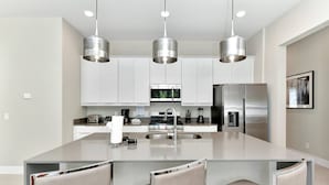 Una cucina moderna con elettrodomestici in acciaio inossidabile, un'isola centrale con posti a sedere e illuminazione a sospensione.