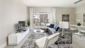 A modern living room with a TV, sofa, coffee table, and dining area. - Precious Villa - 5 min to Disney (Kissimmee)