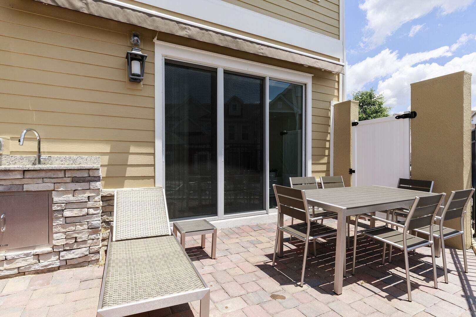 An outdoor patio with a stone fireplace, a table, and chairs.