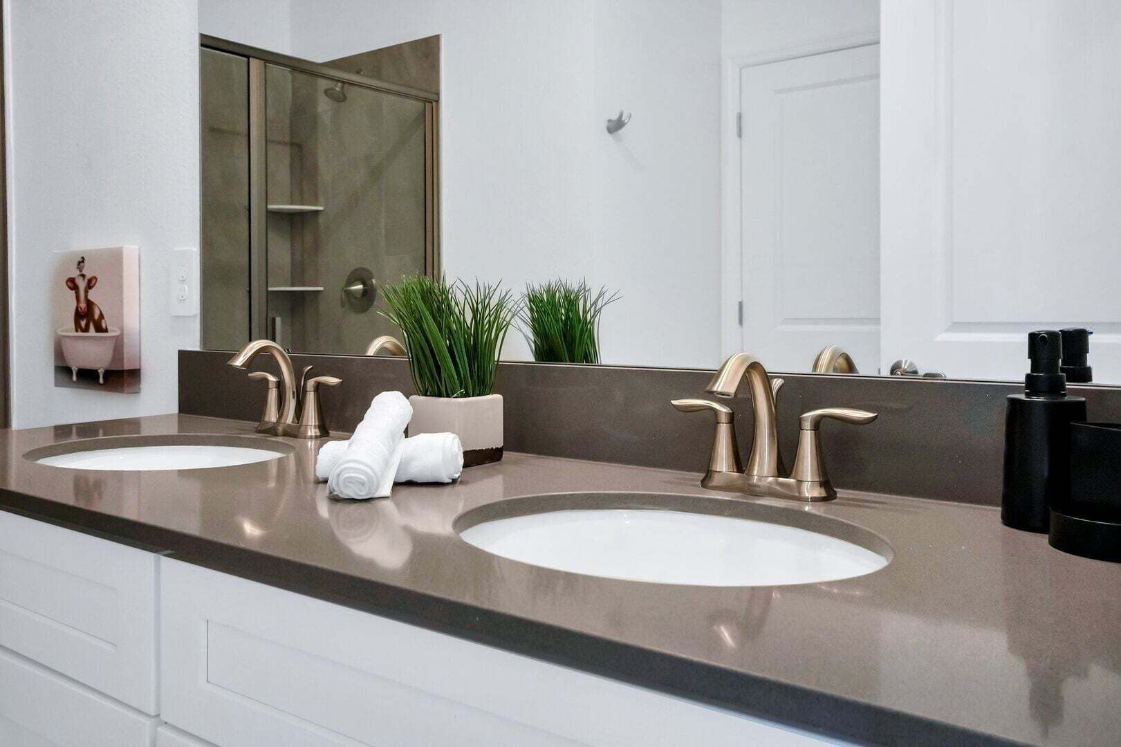 A modern bathroom with two sinks, a large mirror, and a shower.