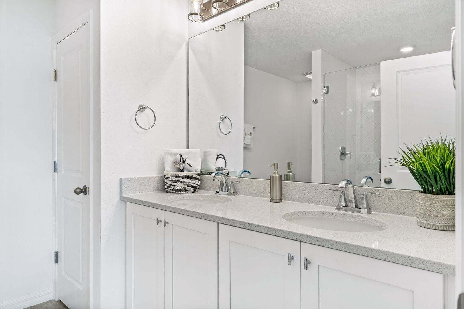 Une salle de bain moderne avec deux lavabos, un grand miroir et une plante en pot.
