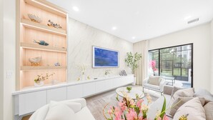 Een moderne woonkamer met een witte bank, een salontafel en een inbouwkast met decoratieve objecten.