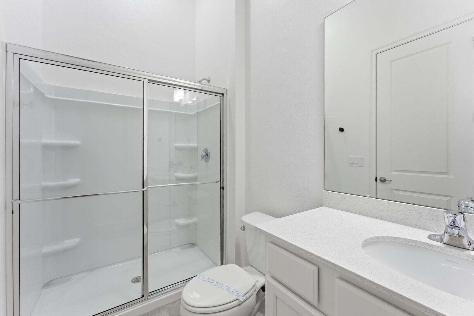 Une salle de bain avec une douche à parois de verre, des toilettes et un lavabo avec un miroir.