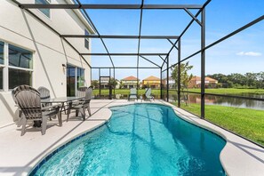 A swimming pool with a covered patio area, outdoor seating, and a view of a residential neighborhood. - Lakeview Home Sleeps 25 (Kissimmee)