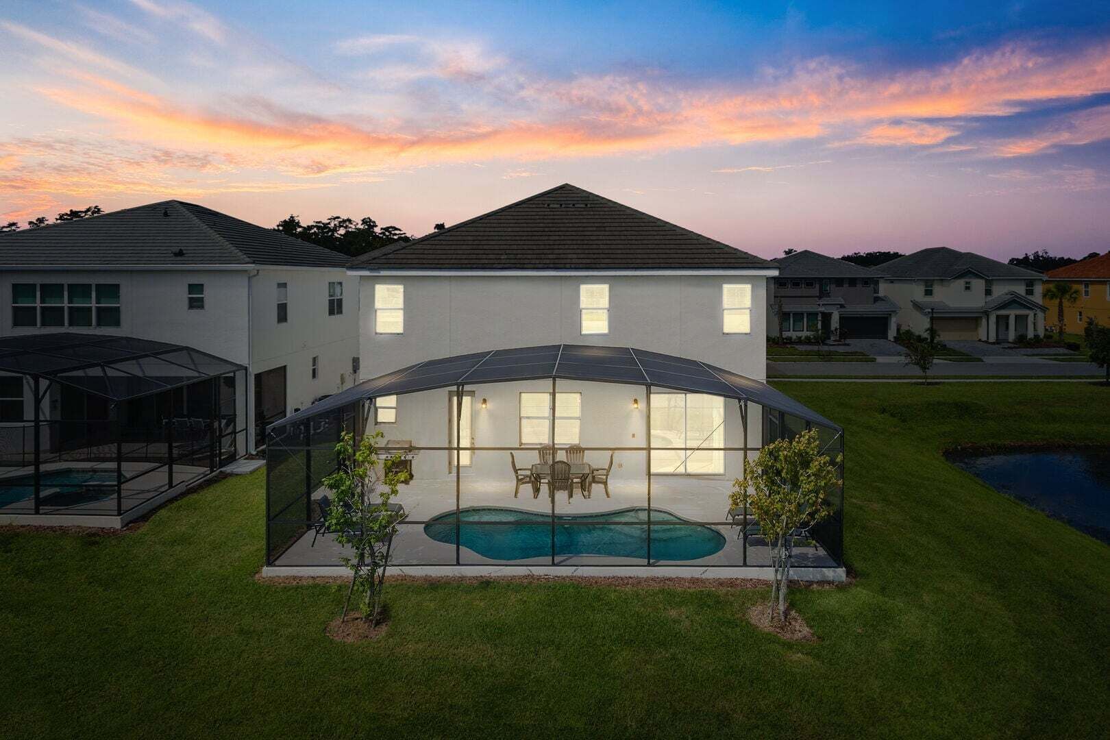 Ein modernes Haus mit einer großen, verglasten Terrasse, einem Swimmingpool und einem gepflegten Rasen.