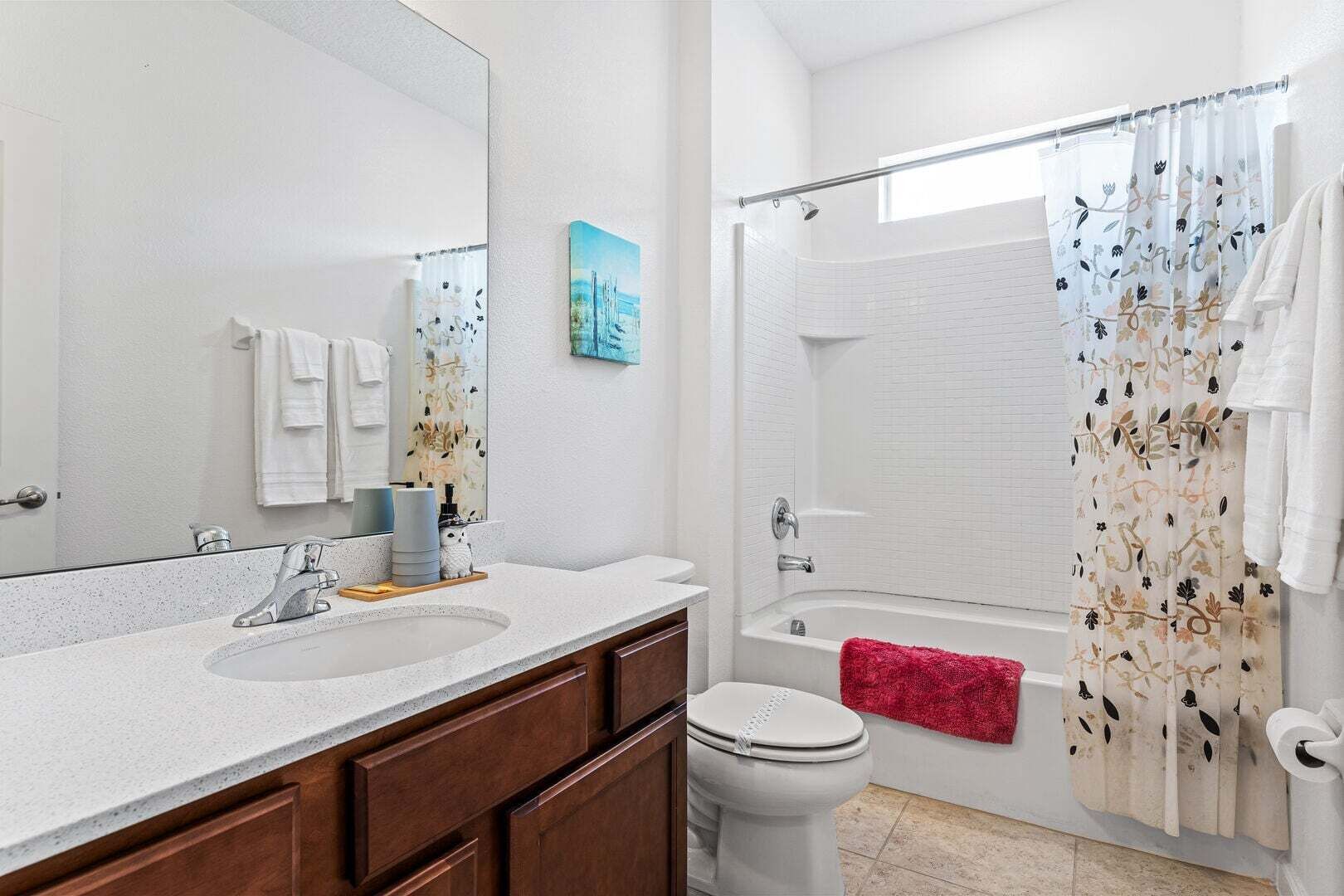 A bathroom with a sink, mirror, toilet, and shower area.