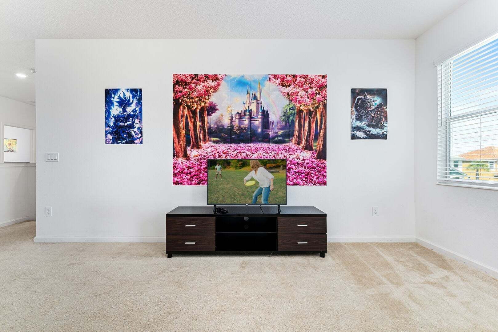A living room with a flat-screen TV on a dark wooden TV stand, surrounded by three framed artworks on the wall.