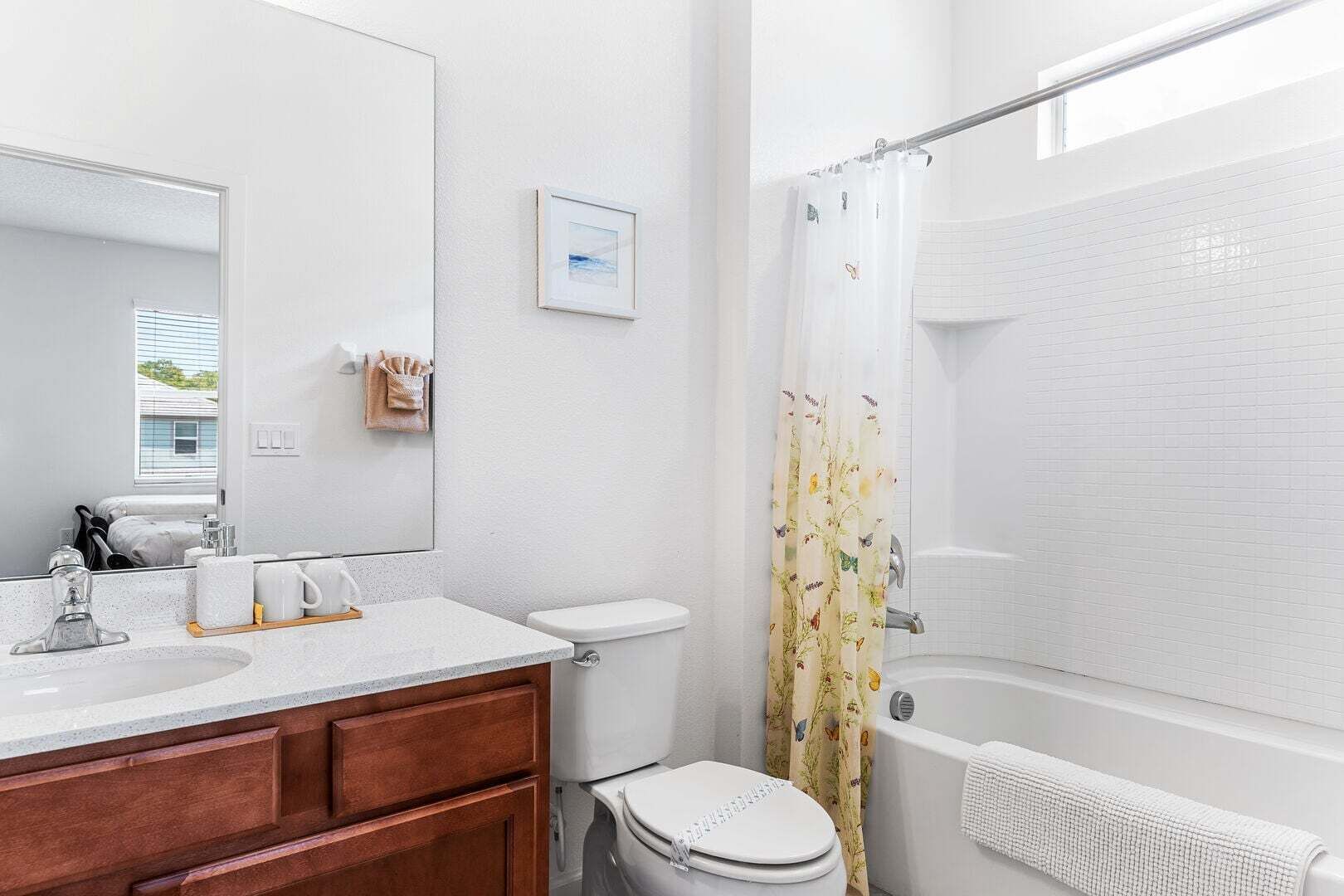 A bathroom with a white sink, mirror, toilet, and shower.