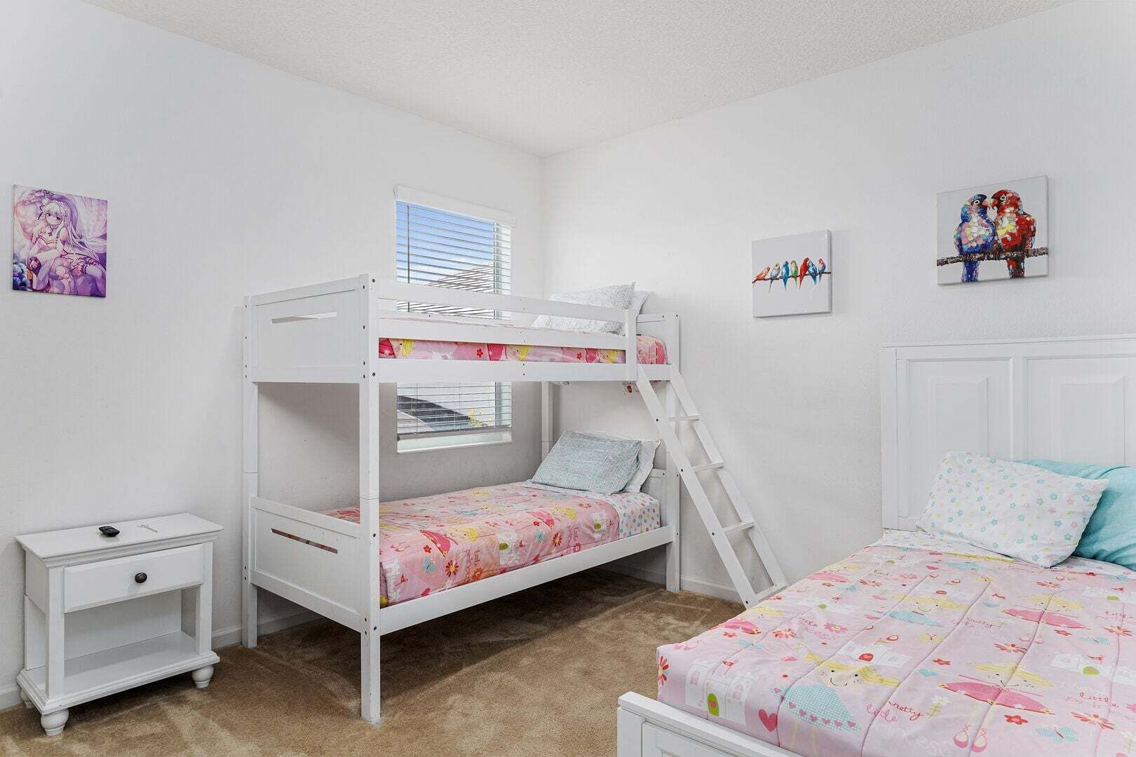 A bunk bed room with a window, a bedside table, and two wall art pieces.