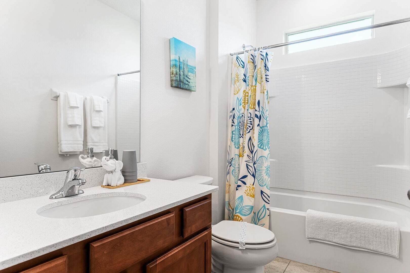 A bathroom with a sink, mirror, toilet, shower, and a towel rack.