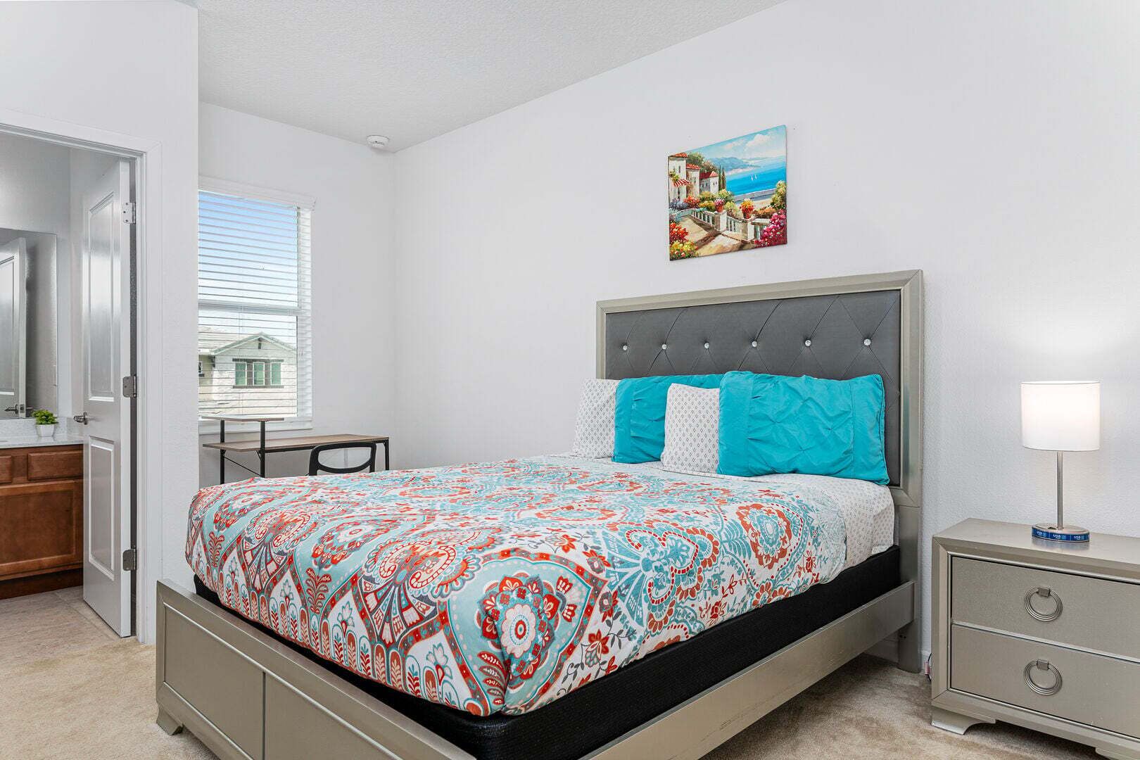 Quarto com uma cama, mesa de cabeceira, escrivaninha e janela.