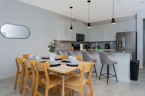 Una cocina moderna con armarios blancos, una isla central e iluminación colgante.
