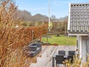 A wooden deck with outdoor furniture, a pergola, and a view of a garden and trees. - "Fenno" - 800m from the sea by Interhome (Hejls)