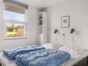 A bedroom with a bed, a window with a view, a white wardrobe, and a wall-mounted lamp. - "Fenno" - 800m from the sea by Interhome (Hejls)