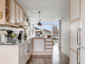 Eine moderne Küche mit Holzausstattung, einem eingebauten Ofen, einer Kaffeemaschine und einem großen Fenster mit Blick nach außen.