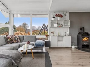 Ein modernes Wohnzimmer mit Sofa, Couchtisch, Kamin und Blick ins Freie.