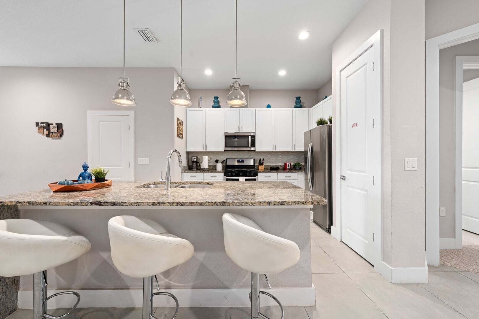 A modern kitchen with a granite countertop, stainless steel appliances, and pendant lighting.