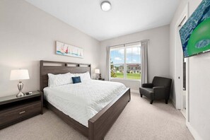 A hotel room with a bed, a nightstand, a chair, a window with a view, and a TV. - Townhouse 4 Bedrooms 5 Min to Disney! (Kissimmee)