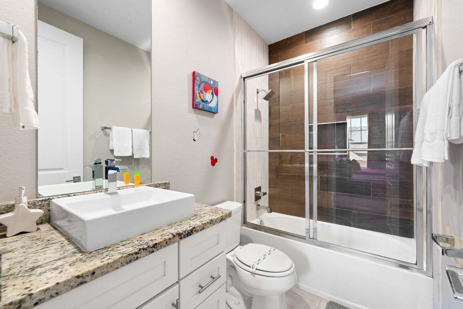 Un baño con un lavamanos grande, un inodoro, una ducha con puerta de vidrio y un espejo.