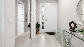 Un pasillo con una puerta blanca, una vitrina de vidrio y una planta en maceta.