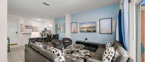 A modern living room with a sofa, armchairs, a coffee table, and a TV.