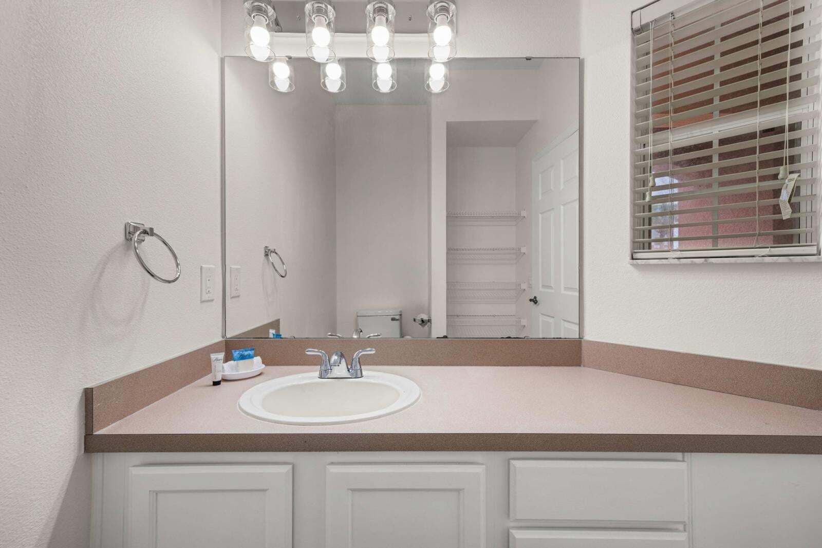 A bathroom with a white sink, a mirror, and a vanity with cabinets.