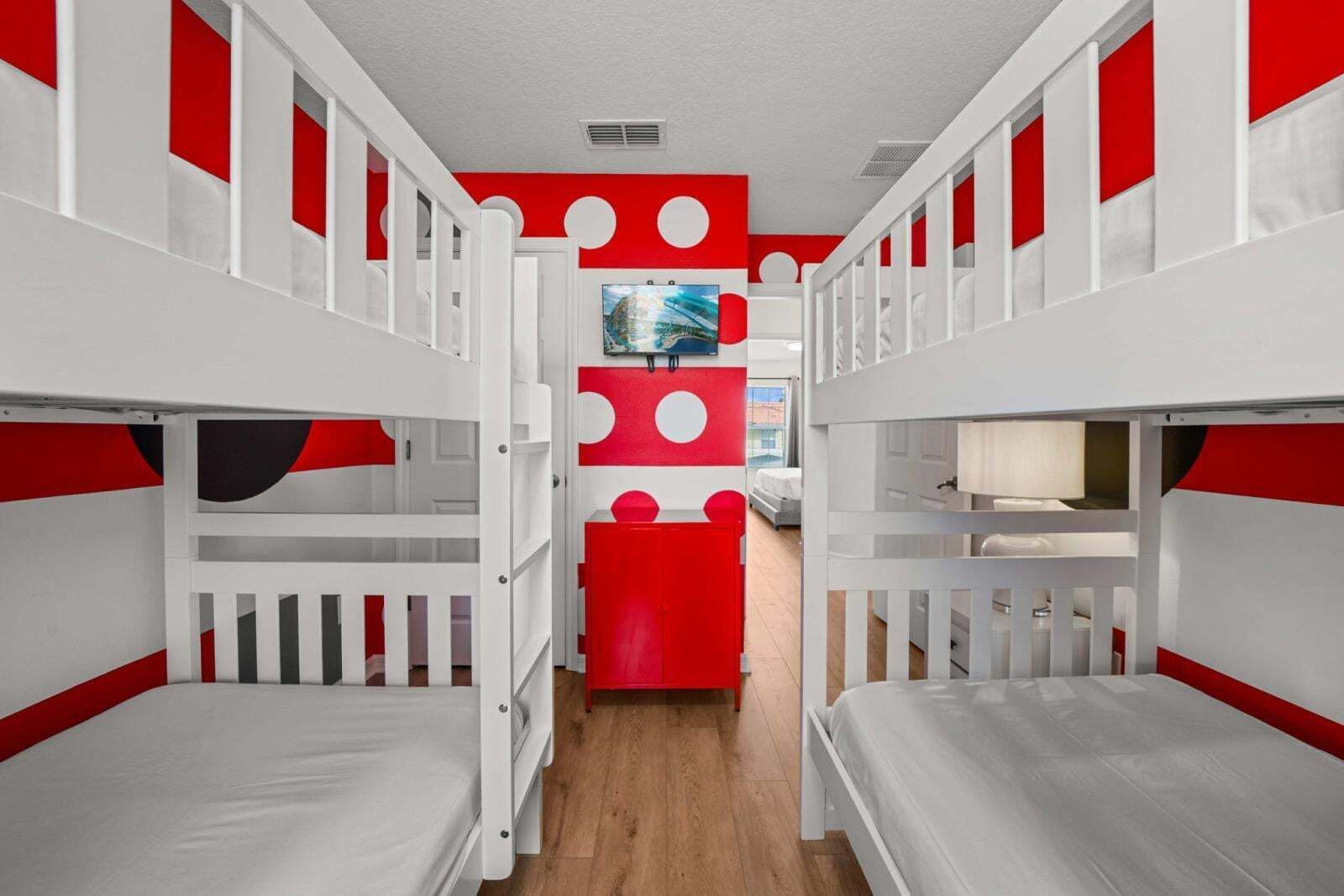 A room with bunk beds, a red accent wall, and a television.