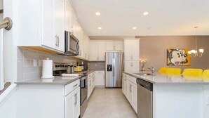 A modern kitchen with white cabinetry, stainless steel appliances, and a central island. - Stylish Home at Amazing Resort! (Kissimmee)