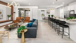Una cocina moderna con barra, zona de estar con sofás y sillas, y mesa de comedor.